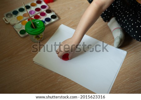 The child draws on a piece of paper with paints. Creative development