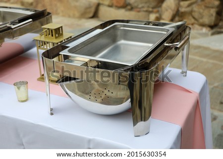 A stainless steel chafing dish or food warmer on top of a buffet table.
