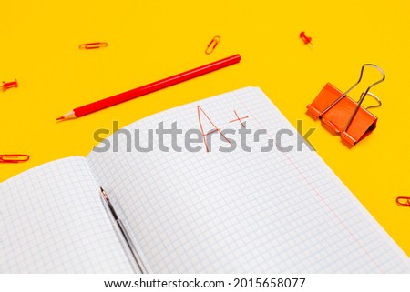 A composition of notebook with an excellent grade on a yellow background. Flat lay. Concept of back to school.