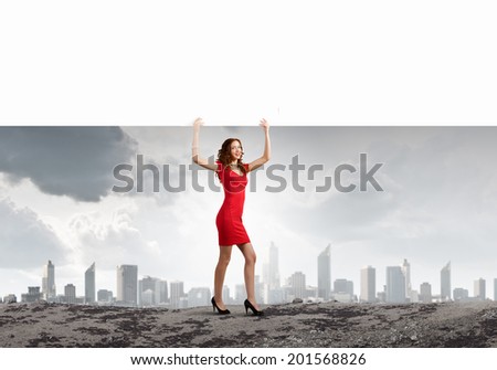 Young woman in red dress holding white blank banner