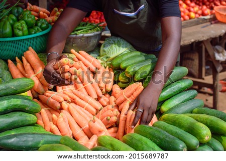 stock photo of female African grocery seller or business woman with apron, standing at her stall in a market, ready to sell to customers