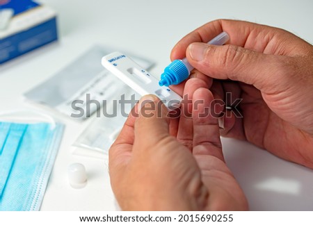  ATK SARS Cov 2 coronavirus rapid antigen test nasal kit. A man doing Covid-19 Self test at home. Hand holding test on white background. Antigen rapid test kit of Covid-19 for selftest at home.