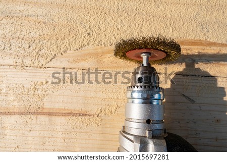 Metal brush, drill and wood planks with sawdust. Tool for making texture and relief for wood.