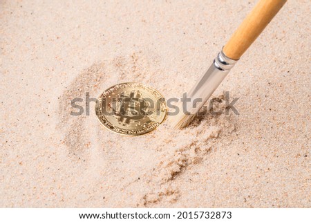 gold bitcoin buried in the sand. cryptocurrency and money