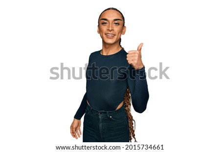 Hispanic transgender man wearing make up and long hair wearing casual clothes smiling happy and positive, thumb up doing excellent and approval sign 