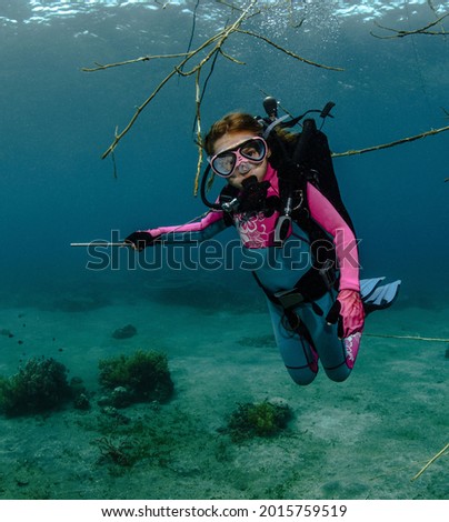 little girl diver shows the direction where to swim underwater in the sea