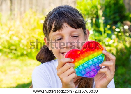 Funny teenage girl playing with rainbow antistress on the street. The push bubble fidget sensory toy is a stress relief toy. Portrait. Close-up.