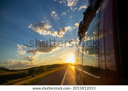 RAPID CITY, SOUTH DAKOTA: Driving Off Into a Colorful Sunset with a Travel Van Royalty-Free Stock Photo #2015812013