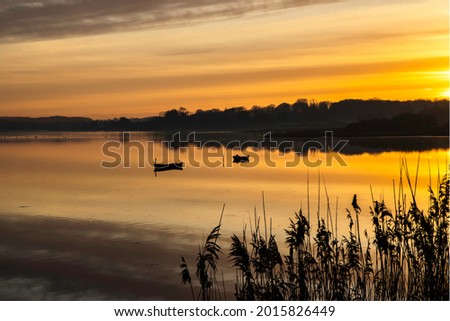Golden sunset with reflections from skies and horizon. Two boats anchored in the waters