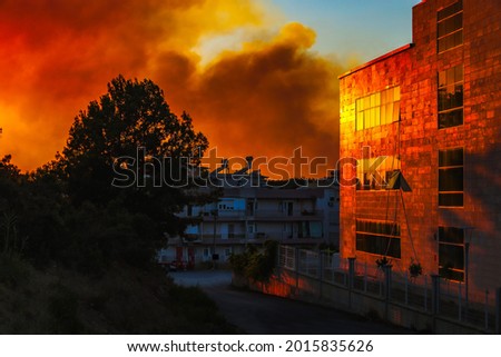 Massive Forest Fire, orange reflection of flames in buildings at night, fire fumes in the city, fire smoke at sunset. Royalty-Free Stock Photo #2015835626
