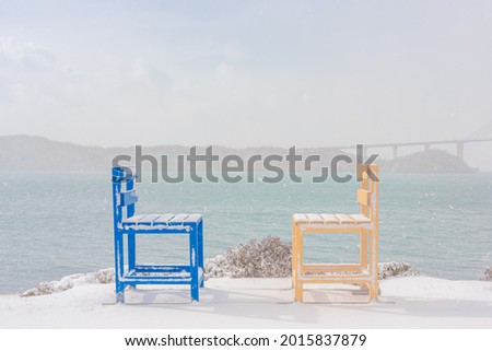 Blue and yellow chairs facing the sea.