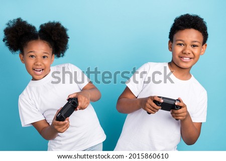 Photo of two little black kids happy positive smile player console joystick isolated over blue color background