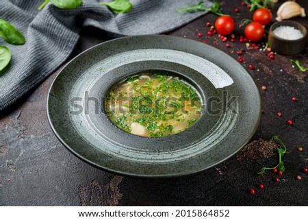 Chicken soup bouillon on black stone bowl on dark concrete table