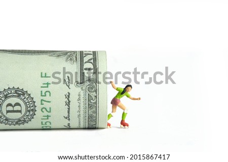 Miniature people toy figure photography. Skateboard winning prize concept. A young skateboarder girl coming out from rolled dollar money paper, isolated on white background. Image photo