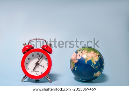 red alarm clock and planet earth on blue background. World time. Time management