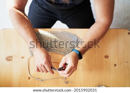 Detail of unrecognizable person using pliers while crafting chain-mail Royalty-Free Stock Photo #2015902031