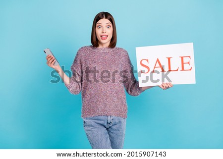 Photo of amazed crazy blogger lady hold phone sale placard open mouth wear sweater isolated blue color background