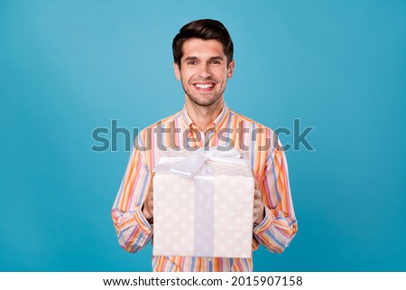Photo of young man happy positive smile hold present box party celebration isolated over blue color background