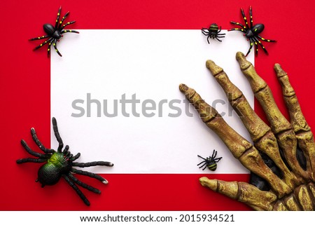 Halloween mock up, blank white sheet of paper with spiders and monsters hand on a red background. Happy Halloween concept.