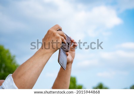 a man takes pictures on the phone against the background of the sky, close-up