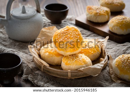 Traditional Chinese Cantonese pastry Sweetheart Cake or Lo Po Beng placed on a bamboo plate on a wooden table. there are also a tea pot and two tea cups as well as some more cakes. Royalty-Free Stock Photo #2015946185