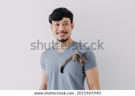 Happy Asian man with his shy Sugar Glider climbing on his body.