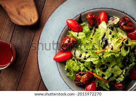 Salad with lettuce and fried duck on wooden background