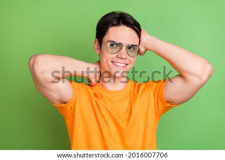 Photo of attractive young happy dreamy man look empty space wear sunglass touch hair isolated on green color background