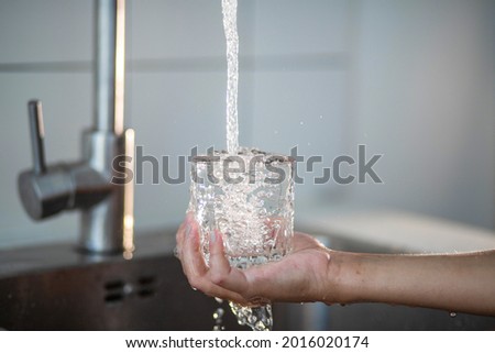 Tap water is poured into a glass, beautiful water splashes, the child's hand holds a glass transparent glass, air bubbles in the water.

