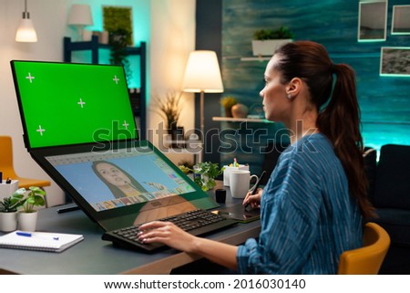 Media project artist working with green screen on display computer monitor at photography studio. Woman using retoucher and chroma key for mockup template background at creative workplace