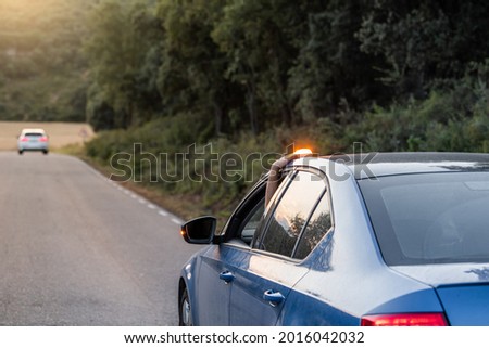 hand placing the new V16 emergency light, which replaces the emergency triangles, broken blue vehicle stopped on the road and with another car in the background Royalty-Free Stock Photo #2016042032