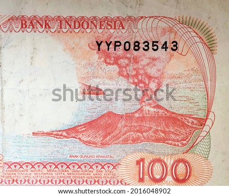 A close-up macro photo of a worn Indonesian banknote of 100 rupiah printed in 1992; in detail the image of the Krakatoa mountain boy.