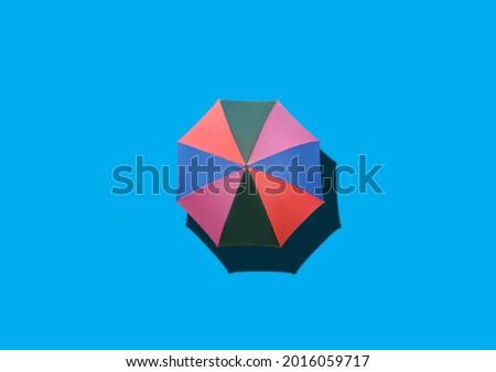 Top view, Single rainbow umbrella isolated on cyan background for stock photo or design, invesment, business, summer concept