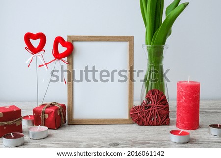 Holiday mock up. Tulip flowers in glass vase with picture frame decor on wooden table background wall at home, close up, Mothers Womans Valentines Day design concept.