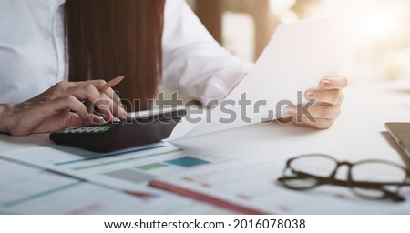 Close up of businesswoman or accountant using calculator to calculate business data, accountancy document and laptop computer at office, business financial concept.