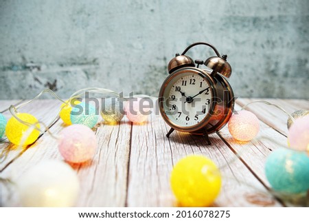 Alarm clock with LED cotton ball decoration on wooden background