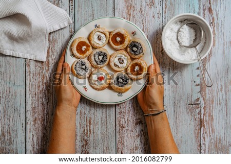Female hands holding rustic plate with freshly homemade pie stuffed with cream cheese, jam, poppy. Cookies ready to eat on wooden table. Delicious traditional Czech pastry.Sweet tasty cakes with sugar Royalty-Free Stock Photo #2016082799