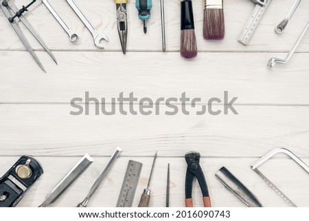 Border frame of work tools on white wooden table with copy space. Top view