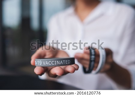 Closeup image of a woman holding and showing Covid-19 vaccination wristband for health care concept