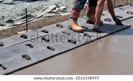 Workers stamping a concrete patio floor Royalty-Free Stock Photo #2016148997