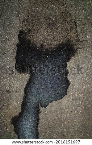 A puddle and wet spots on the asphalt in the form of the head of a black man with a large light haircut. Illustration of visual illusion - pareidolia.