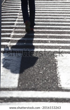 Feet of a man walking on zebra crossing pedestrian crossing