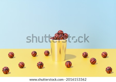 several basketballs in a glass and on the floor on a blue and yellow background. sport and competition.