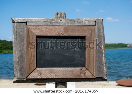 Empty black board on white sand beach with warm sunlight in the netherlands