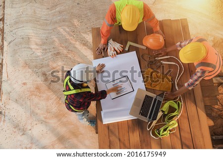 Construction engineers supervising progress of construction project stand on new factory,Engineering Consulting People on construction site holding blueprint in his hand. Building inspector. Construct Royalty-Free Stock Photo #2016175949
