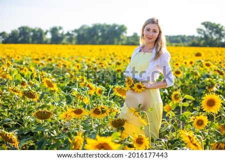 Portrait of the beautiful woman in sunflowers on a background of the sky, Europe