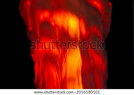 Orange backlit fabric. Fabric imitating fire. Orange background. Red fabric texture.