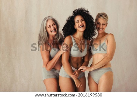 Happy women of different ages embracing their natural bodies. Group of body positive women wearing underwear and standing together. Women posing against a studio background Royalty-Free Stock Photo #2016199580