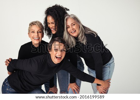 Body positive women of different ages celebrating their natural bodies in a studio. Four confident and happy women smiling cheerfully while wearing jeans against a white background. Royalty-Free Stock Photo #2016199589