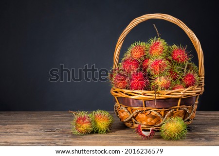 Fresh sweet red rambutan Put in a basket on an old wooden table with a dark background, with space for copying text.